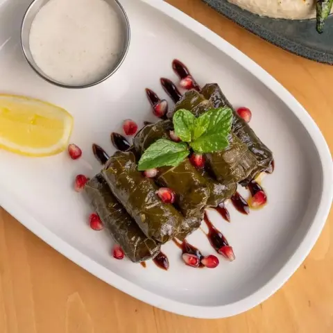 ورق عنب "النخبة".. سر الخلطة الناطعة والترف المذاب! 🍋🌿 لعشاق المذاق الذي لا يُنسى، نقدم لكم ورق العنب المحضر يدوياً بكل إتقان وشغف. نجمع فيه بين جودة الورق المختار وعمق النكهة التي صُقلت عبر أكثر من 7 سنوات من الخبرة. ✨ ما الذي يميز ورق العنب لدينا؟ طعم "ناطع" بامتياز: حشوة غنية متبلة بعناية، تتميز بنكهة عميقة وموزونة تجمع بين حموضة الليمون المنعشة وحلاوة دبس الرمان الفاخر. اللف الاحترافي: حبات متناسقة، صغيرة، ومرتبة بدقة متناهية تعكس مهارة اليد الخبيرة في تقديم الأفضل دائماً. القوام الذائب: مطهو ببطء لينتج ورقاً طرياً جداً وحشوة تذوب في الفم كالحرير، مع لمعة زيت الزيتون البكر التي تزيد من فخامة الطبق. التقديم الملكي: نُزين أطباقنا بحبات الرمان الياقوتية والنعناع الطازج، ليكون الطبق لوحة فنية تُبهر ضيوفكم قبل تذوقها. لماذا تطلبين ورق عنب "إتقان السبع سنوات"؟ نكهة أصلية: نفس منزلي عميق وخلطة ناطعة لا تجدينها في المطاعم التقليدية. جودة الضيافة: رفيق مثالي لـ السمبوسة المقرمشة وأطباق اللحم والدجاج، ليكمل جمال مائدتك. ترتيب يبيض الوجه: يصلكِ الطبق منسقاً وجاهزاً للتقديم المباشر في مناسباتكِ الراقية.
